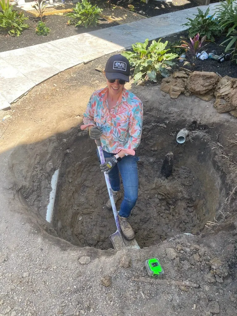 Eva on site digging a planting hole in a garden bed
