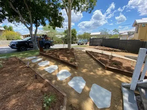 Garden path under construction with stepping stones and timber sleeper edging being set in place