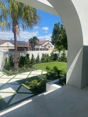 Modern white arched courtyard with large-format pavers, lawn and tropical planting