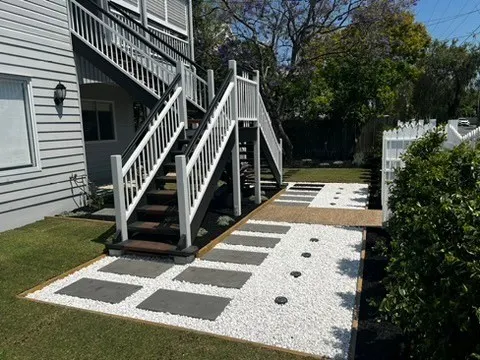 Paver and white pebble pathway leading to the stairs of a Queenslander home