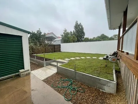 Raised garden bed built from timber sleepers beside a lawn and garden shed